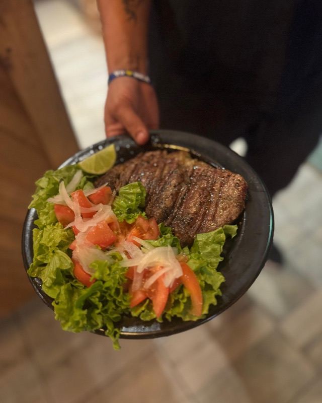 Bife a la parrilla con ensalada de lechuga, tomate y cebolla
