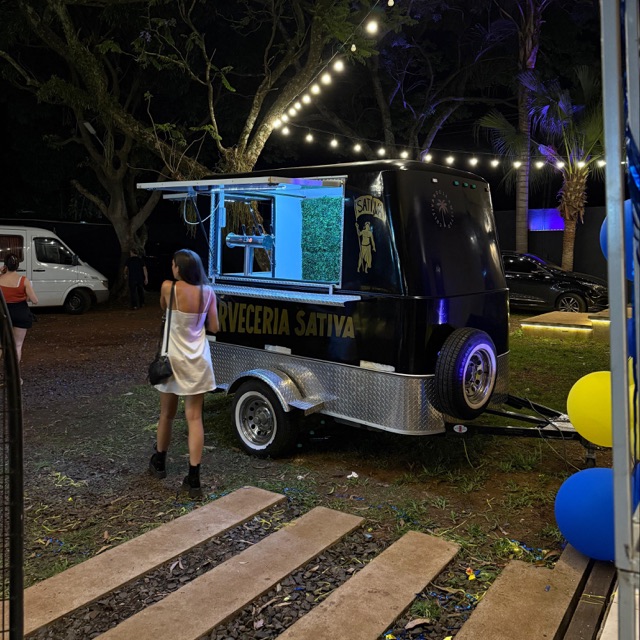 El food truck de cerveza completo, estacionado en un parque con luces y globos