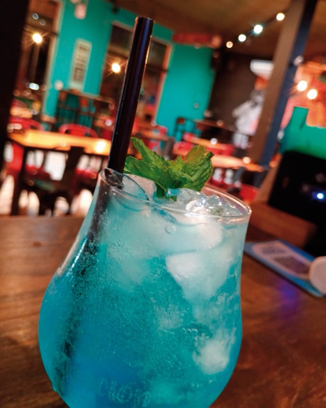 Trago azul con hielo y menta, con el salón turquesa de Cuna de Canoas de fondo